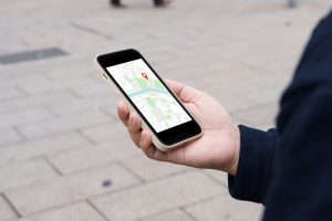 Person hält ein Smartphone mit einer Navigations-App in der Hand