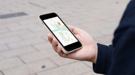 Person hält ein Smartphone mit einer Navigations-App in der Hand