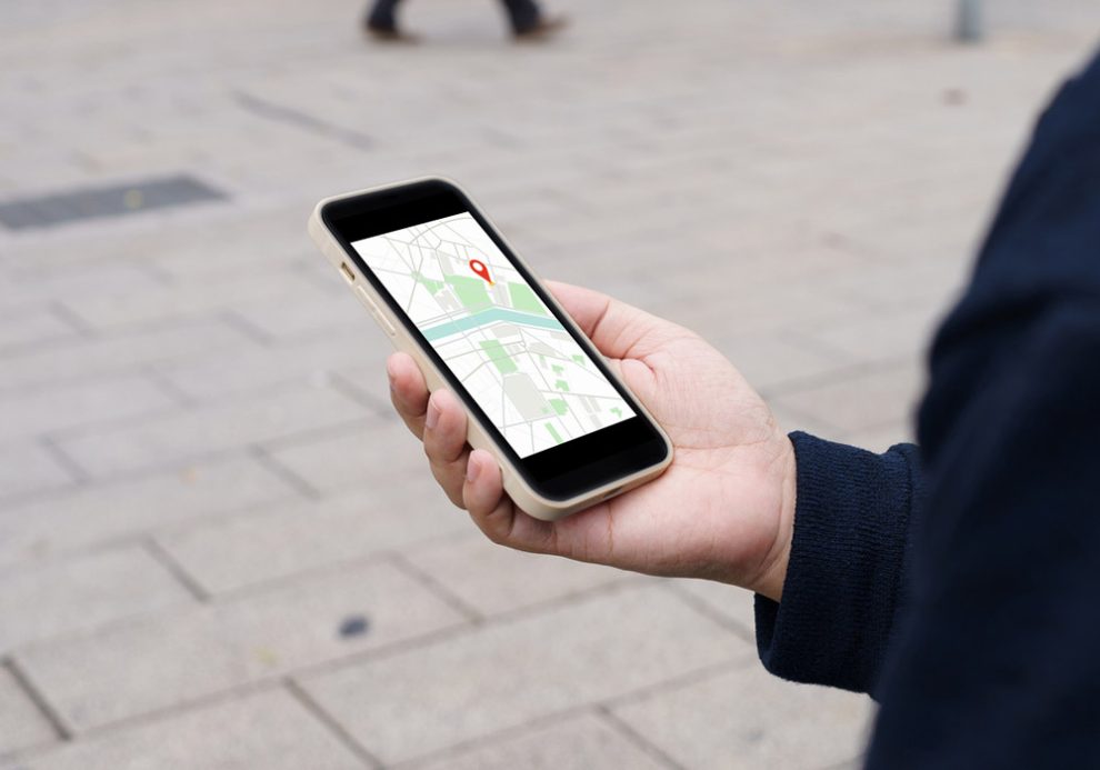 Person hält ein Smartphone mit einer Navigations-App in der Hand