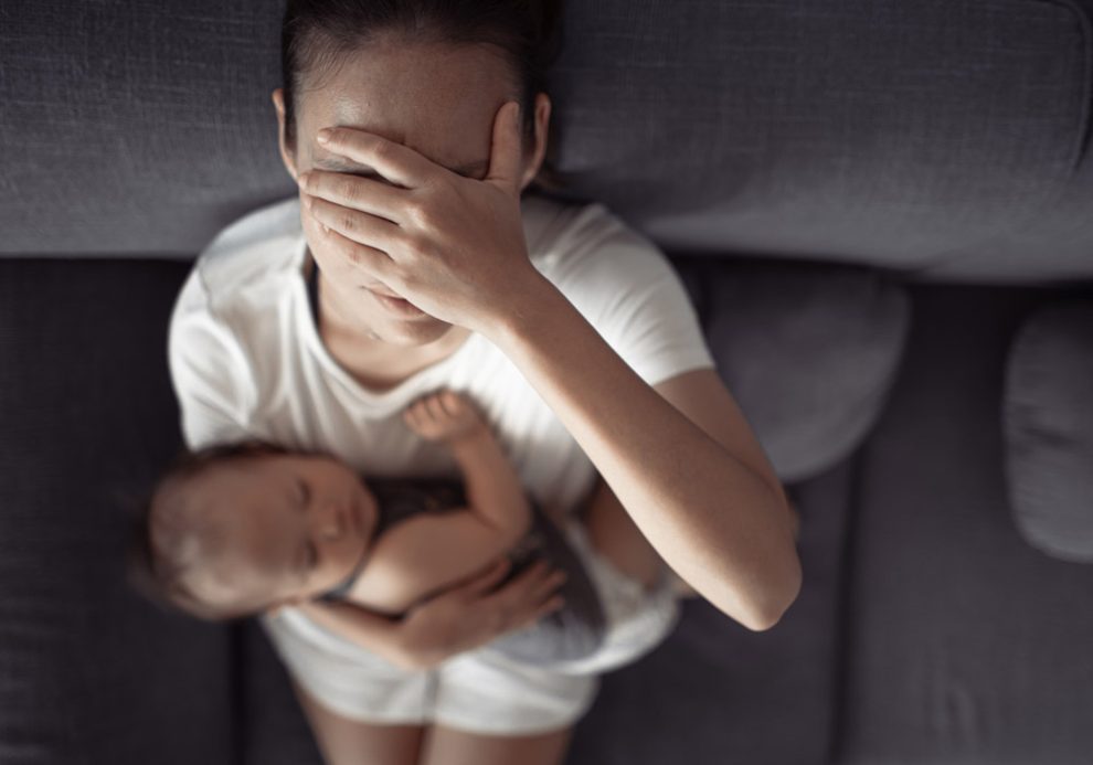 Erschöpfte oder traurige Mutter mit Säugling im Arm