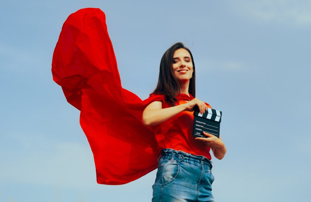 Frau mit Superheldencape und Regieklappe