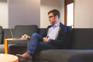 Mann auf Sofa an einem Laptop