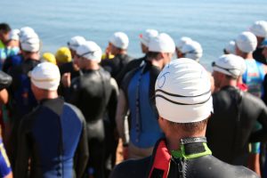 Teilnehmer eines Triathlons in Neoprenanzügen vor dem Start