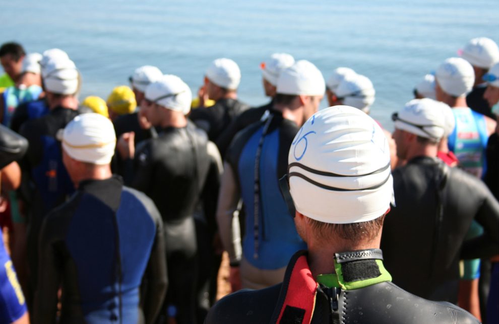 Teilnehmer eines Triathlons in Neoprenanzügen vor dem Start