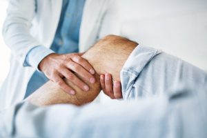 Arzt untersucht Knie eines Patienten