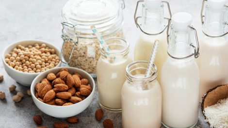 Schalen mit Mandeln, Sojabohnen und Haferflocken sowie Flaschen mit daraus hergestellter Milch