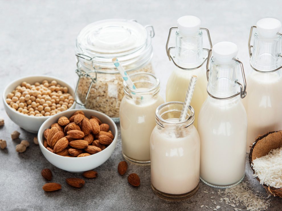 Schalen mit Mandeln, Sojabohnen und Haferflocken sowie Flaschen mit daraus hergestellter Milch