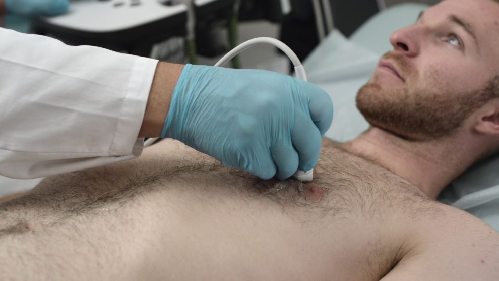 Ultrasound: A doctor checks a man's chest with an ultrasound machine. Diagnosis of respiratory lung and heart diseases. Examination of the body in the clinic office. Checking the status of sonograms