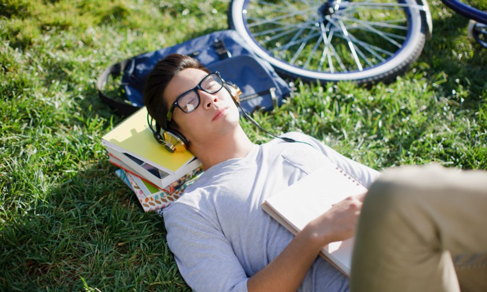 Student liegt in der Sonne und hört Musik, statt zu lernen