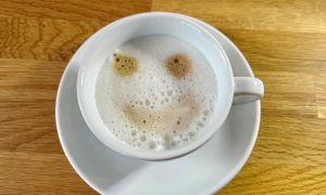 Foto einer Tasse Kaffee mit Gesichtsmuster im Milchschaum