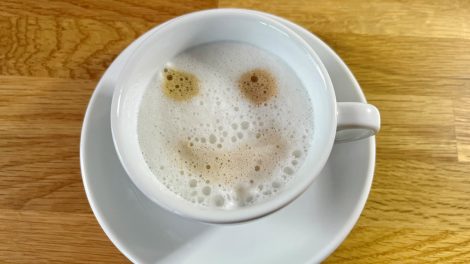 Foto einer Tasse Kaffee mit Gesichtsmuster im Milchschaum