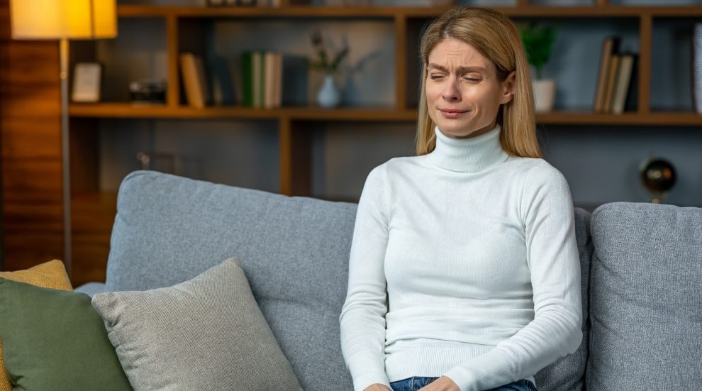 Traurige junge Frau auf einem Sofa