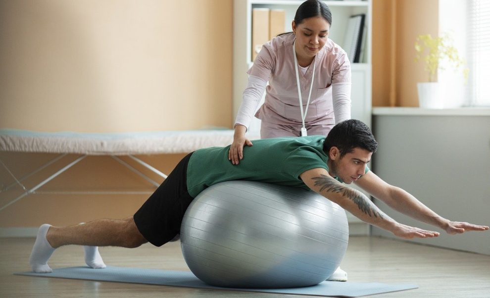 Mann bei einer Ballübung mit einer Chiropraktikerin