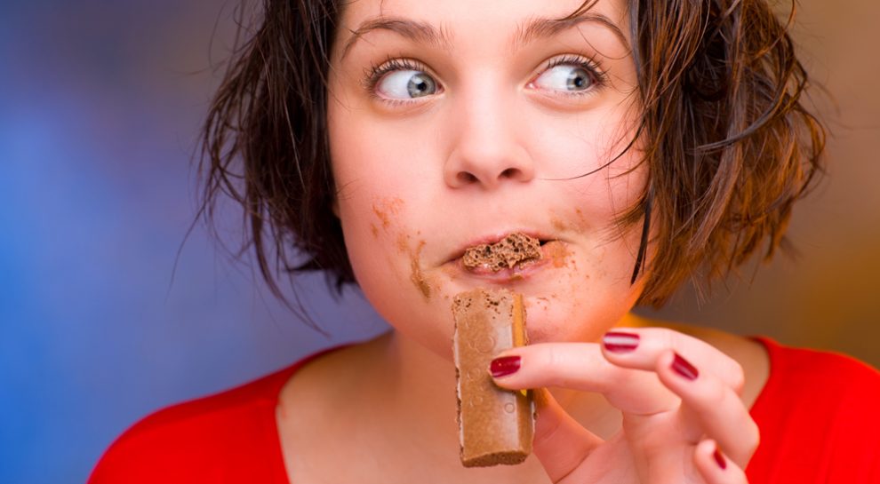 Foto einer jungen Frau, die Schokolade verschlingt